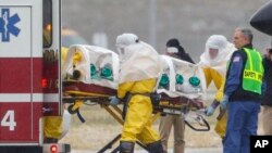 Health workers in protective suits transport Dr. Martin Salia, a surgeon working in Sierra Leone who had been diagnosed with Ebola, at Nebraska Medical Center in Omaha, Neb., Nov. 15, 2014. 