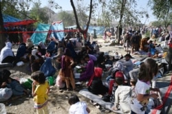 Internally displaced Afghan families, who fled from Kunduz and Takhar province due to battles between Taliban and Afghan security forces, sit in a field in Kabul, Aug. 9, 2021.