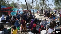 Internally displaced Afghan families, who fled from Kunduz and Takhar province due to battles between Taliban and Afghan security forces, sit in a field in Kabul, Aug. 9, 2021.