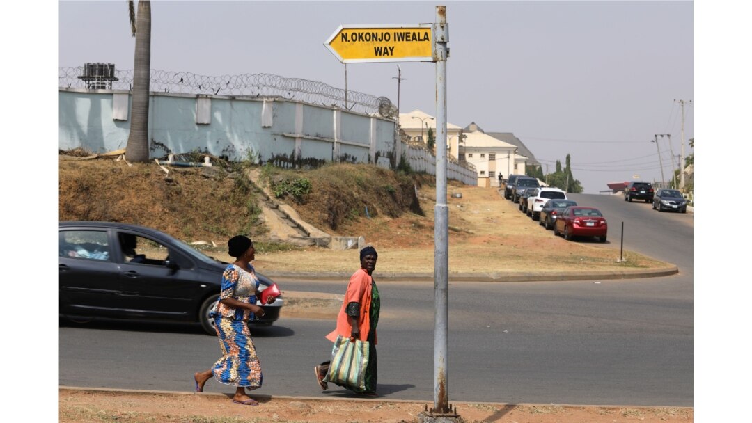 Two women ran across a street named after Ngozi Okonjo-Iweala, in Wuye district in Abuja, Nigeria, Feb. 15, 2021.