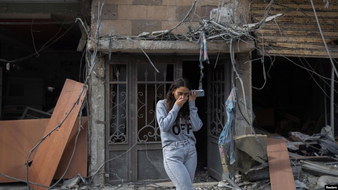 Riwa Kassem Baher habla por teléfono móvil mientras se encuentra frente a su casa dañada en un ataque israelí, después del alto el fuego entre Israel y Hezbolá, en Tiro, sur del Líbano, el 29 de noviembre de 2024. REUTERS