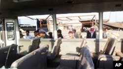 Iraqis look inside a bus damaged from shrapnel after a booby-trapped motorcycle exploded near a group of day laborers waiting for work in the Shi'ite district of Sadr City, January 5, 2012.