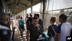 En esta foto del 2 de agosto de 2019, migrantes regresan a México mientras otros hacen fila para solicitar asilo en Estados Unidos, al pie del puente fronterizo Puerta México en Matamoros, Tamaulipas, que cruza a Brownsville, Texas.