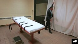 FILE – Larry Greene, public information director of the Southern Ohio Correctional Facility, demonstrates how a curtain is pulled between the death chamber and witness room at the prison in Lucasville, Ohio, in 2005. Ohio plans to resume executions in January 2017.