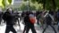 Masked youths face off with French police during a demonstration against the French labor law proposal in Paris, France, as part of a nationwide labor reform protests and strikes, April 28, 2016.