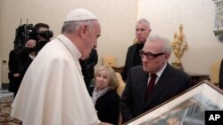 Pope Francis looks at a painting given to him as a gift from director Martin Scorsese, right, on the occasion of their private audience at the Vatican, Nov. 30, 2016. Francis has met with Scorsese, whose new film, "Silence," about Jesuit missionaries in 17th-century Japan, was screened this week in Rome.