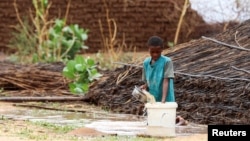 FILE - A displaced Sudanese child pours water at Zamzam camp, in North Darfur, Sudan, Aug. 1, 2024. 