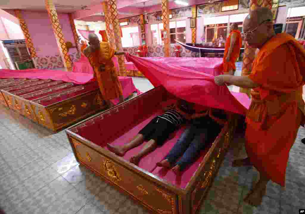 Los monjes cubren a los fieles que descansan en ataúdes en el templo de Takien en los suburbios de Bangkok, Tailandia, el lunes 31 de diciembre de 2018. Los fieles creen que la ceremonia del ataúd, que simboliza la muerte y el renacimiento, los ayuda a librarse de la mala suerte y nacen de nuevo para un nuevo comienzo en el año Nuevo. 