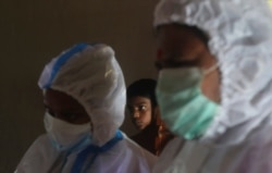 A boy looks on as health workers screen people for COVID-19 symptoms at a residential building in Dharavi, one of Asia's biggest slums, in Mumbai, India, Aug. 7, 2020.