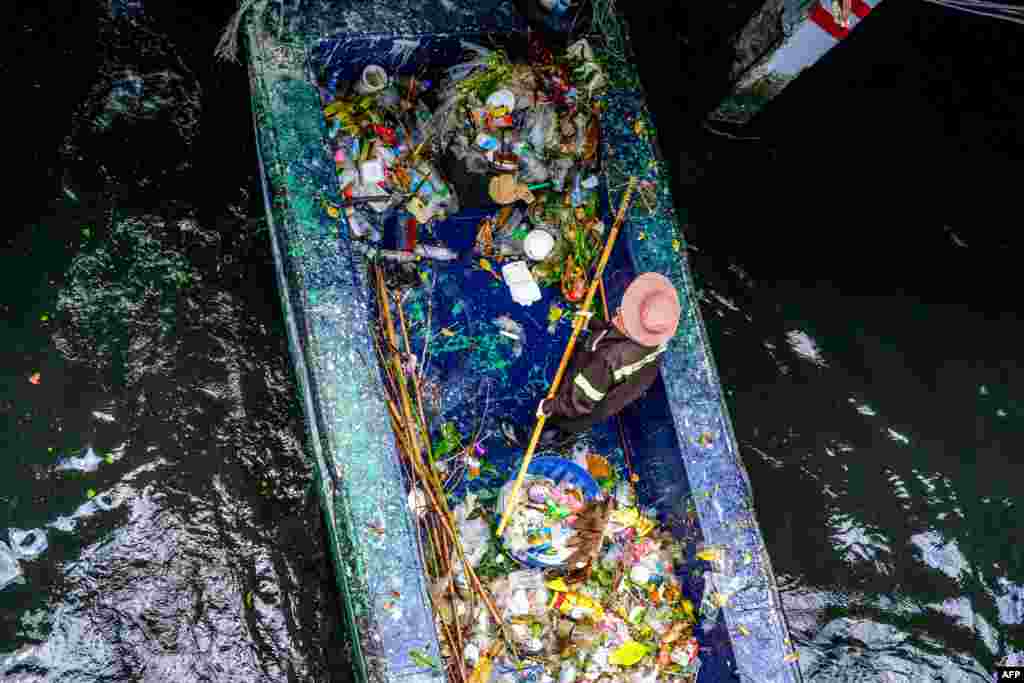 A municipal worker uses a net to pick out garbage from a canal in Bangkok.