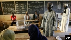 A voter presents his identification to election workers at a polling station in Senegal, Feb. 25, 2007. President Abdoulaye Wade was elected to the second of two constitutional terms.