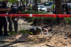Israeli bomb squad unit inspect the site where a rocket fired from the Gaza Strip hit a sidewalk, in Ashdod, Israel, May 19, 2021.