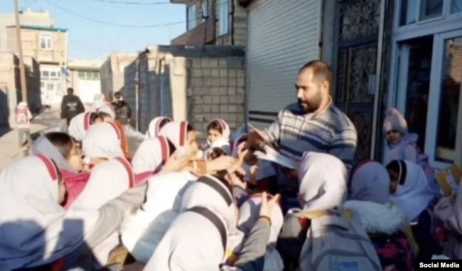 Müctəba Əbdüli məktəbli uşaqlara kitab paylarkən