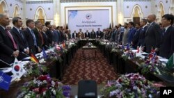 FILE - Afghan President Ashraf Ghani, center, and delegates stand for the national anthem during the Kabul Process conference, at the Presidential Palace in Kabul, Afghanistan, June 6, 2017.