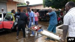 Quelques personnes transportent un blessé après une fusillade à Conakry, le 7 novembre 2018.