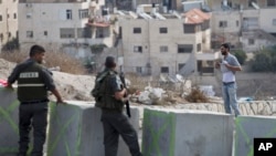 Un Palestinien soulève sa chemise devant des policiers qui patrouillent à la frontière israélienne dans le quartier d'Issawiyeh in Jérusalem, Oct. 20, 2015. (AP Photo/Ariel Schalit)