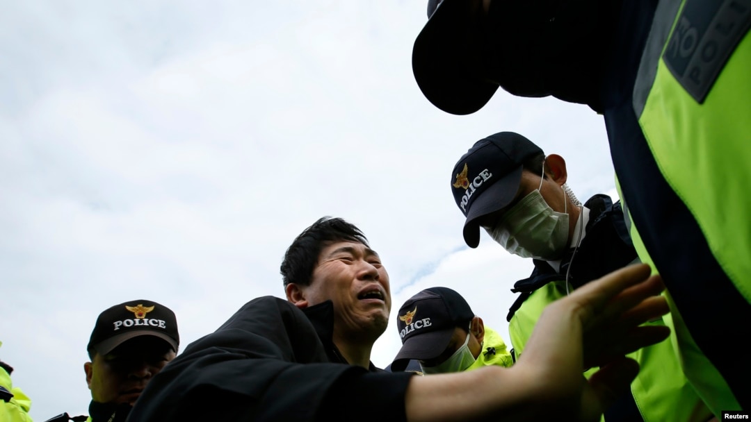 A family member of a passenger missing after the South Korean ferry "Sewol" capsized is blocked by police during a protest in Jindo calling for a meeting with President Park Geun-hye and demanding the search and rescue operation be speeded up, April 20, 2014.
