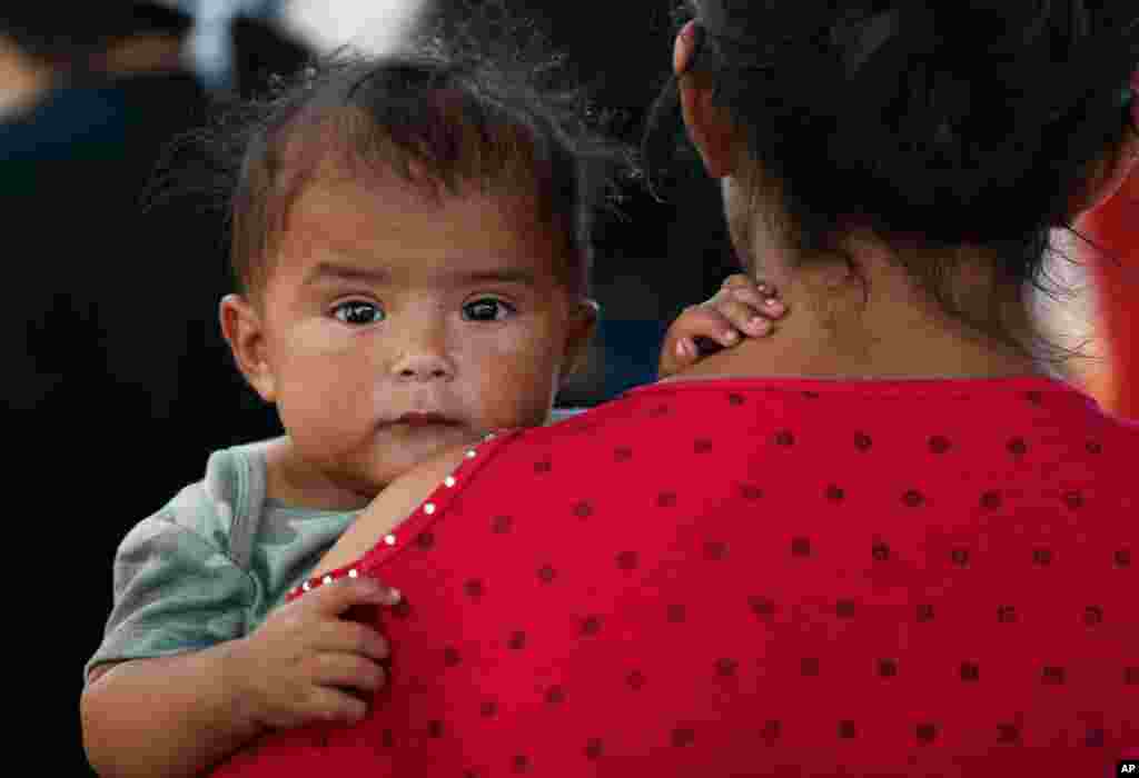 A Honduran migrant mother and her 7-month-old child stand in line to board a bus that will take them and other migrants to Monterrey, from an immigration center in Nuevo Laredo, Mexico, July 18, 2019.