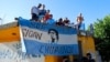 Fans stand on a roof of a house along the route of the motorcade carrying the remains of football star Diego Maradona to the Jardin de Bellavista cemetery in Buenos Aires, Argentina, Nov. 26, 2020. 