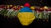 An anti-Yanukovych protester, wearing a Ukrainian flag with the name of his village written across it, places flowers at a memorial for the people killed in clashes in Kyiv's Independence Square, Feb. 25, 2014. 