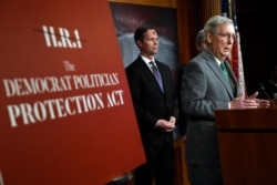 FILE - Senate Majority Leader Mitch McConnell of Kentucky voices opposition to a House-passed election reform bill as Rep. Rodney Davis, R-Ill., listens at left, March 6, 2019.