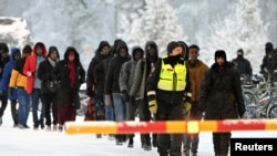 Guardias fronterizos finlandeses escoltan a los migrantes en el cruce internacional en Salla, norte de Finlandia, el 23 de noviembre de 2023.