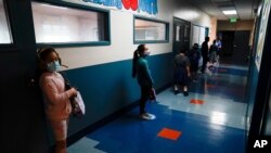 Los Angeles Unified School District students stand in a hallway socially distance during a lunch break at Boys & Girls Club of Hollywood in Los Angeles, Aug. 26, 2020.