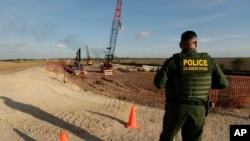 A U.S. Border Patrol agent stands over a construction site for a new section of levee border wall along the U.S.-Mexico border, Nov. 7, 2019, in Donna, Texas. 