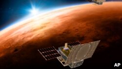 Esta ilustración distribuida por NASA el 29 de marzo de 2018 muestra los satélites gemelos Mars Cube One sobrevolando Marte, con el sol y la Tierra en el fondo. (NASA/JPL-Caltech via AP)