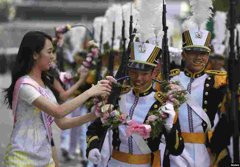 Para kadet dari Akademi Angkatan Laut Korea menerima kalung bunga dari Miss Korea selama parade yang menandai peringatan hari jadi ke-65 Pasukan Bersenjata Korea di Seoul (1/10).