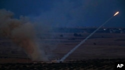 In this photo taken from the Turkish side of the border between Turkey and Syria, in Ceylanpinar, Sanliurfa province, southeastern Turkey, Turkish forces fire rockets towards targets in Ras al-Ayn, Syria, Oct. 15, 2019. 