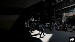 Una mujer con tapaboca cruza una calle en Caracas, el 26 de diciembre de 2021. [Foto: AP]