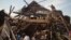 Men investigate the remains of a house struck hours earlier by deadly mortar fire, sparking angry protestors to take to the streets, in Goma, DRC, Aug. 24, 2013. 