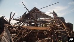 Men investigate the remains of a house struck hours earlier by deadly mortar fire, sparking angry protestors to take to the streets, in Goma, DRC, Aug. 24, 2013. 