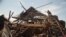 FILE - Men investigate the remains of a house struck hours earlier by deadly mortar fire, sparking angry protestors to take to the streets, in Goma, DRC, Aug. 24, 2013. 