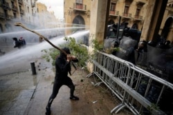 Anti-government demonstrators clash with riot police at a road leading to the parliament building in Beirut, Lebanon, Jan. 18, 2020.