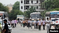 Laborers walk along a street next to a Maruti Suzuki India Ltd. manufacturing plant in Manesar in the northern state of Haryana, India, Aug. 2, 2019.