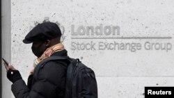 FILE - A man wearing a protective face mask walks past the London Stock Exchange Group building in the City of London financial district, London, Britain, March 9, 2020. 