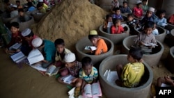 Rohingya refugee children attend recitation classes of the holy Quran in a newly opened madrasa, or religious school, amid material stocked for constructing latrines in Balukhali refugee camp, Bangladesh, Monday, Oct. 30, 2017. 