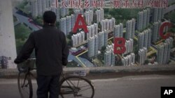 Seorang warga tengah mengamati gambar peta proyek perumahan yang dipajang di pembatas wilayah sebuah konstruksi di Beijing, TIongkok, 17 Januari 2013. (AP Photo/Alexander F. Yuan). Laju pertumbuhan ekonomi Tiongkok dilaporkan meningkat menjadi 7,9 persen pada kuartal ke-4 tahun 2012 yang lalu.