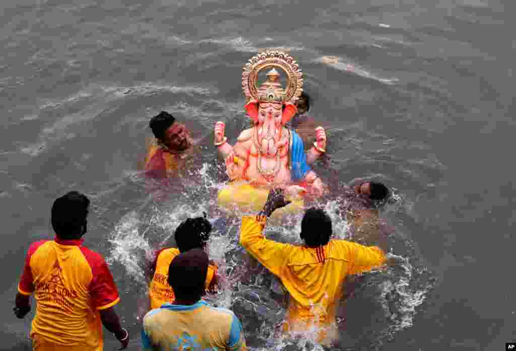 گروهی از پیروان هندو، مجسمه مقدسی را به آب دریا می‌سپارند. 