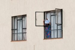 FILE - A young lady holds a sign asking for help after the Ministry of Health extended the detention period of people in quarantine to 28 days at a government-designated quarantine facility in Nairobi, April 4, 2020.