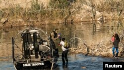 Sekelompok migran dijemput oleh petugas dari Texas setelah terdampar di tepian sungai selama berjam-jam di Eagle Pass, Texas, pada 18 Januari 2024. (Foto: Reuters/Go Nakamura)