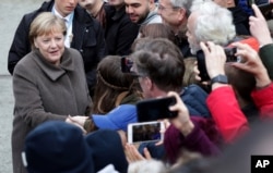 German Chancellor Angela Merkel, left, shakes hands with visitors prior to a memorial service in the chapel at the Berlin Wall Memorial in Berlin, Germany, Nov. 9, 2019.
