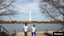 With the Washington Monument in the background, a couple walks hand in hand along the Tidal Basin in Washington, March 9, 2016. 