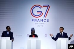 FILE - French President Emmanuel Macron, right, African Development Bank President Akinwumi Adesina, left, and UNICEF ambassador Angelique Kidjo during the G7 summit in Biarritz, southwestern France, Aug. 25, 2019.