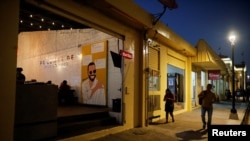 La gente camina frente a un restaurante con un mural que representa al presidente de El Salvador, Nayib Bukele, que se postula para la reelección, antes de las elecciones presidenciales y del Congreso, en Mejicanos, El Salvador, el 29 de enero de 2024.