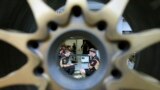 Lotus mechanics, seen through a wheel, talk to one another at the garage of the Marina Bay City Circuit in Singapore. The Formula One Singapore Grand Prix will be held on Sept. 22 in the city-state.