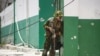 FILE - A Kenyan police officer stands outside the General Hospital during a joint operation with Haitian police, in Port-au-Prince, Haiti, July 29, 2024. Gang members set fire to the hospital on Feb. 13, 2025. 