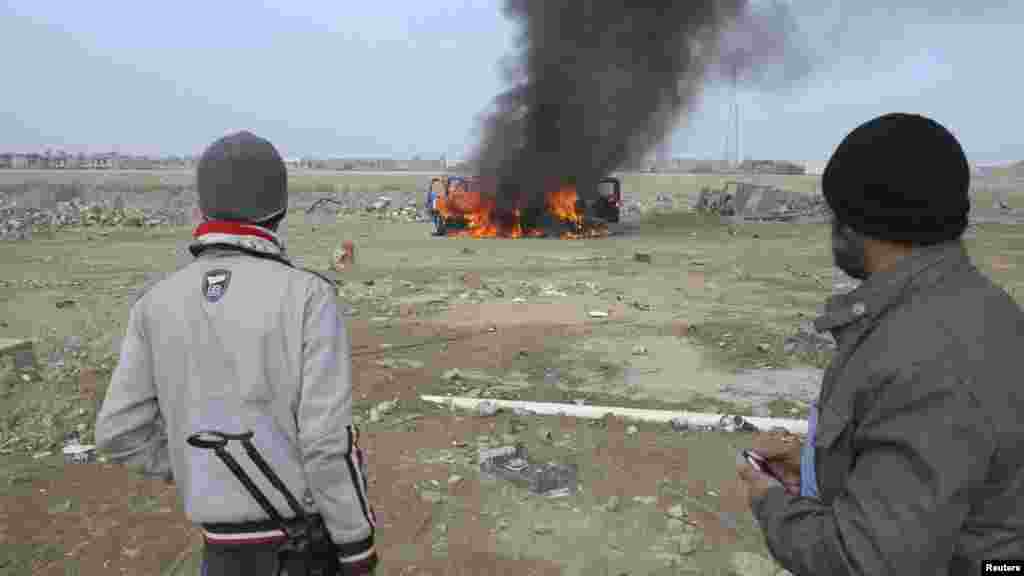 Sunni Muslim fighters watch as a police vehicle burns during clashes in Ramadi, Jan. 2, 2014.